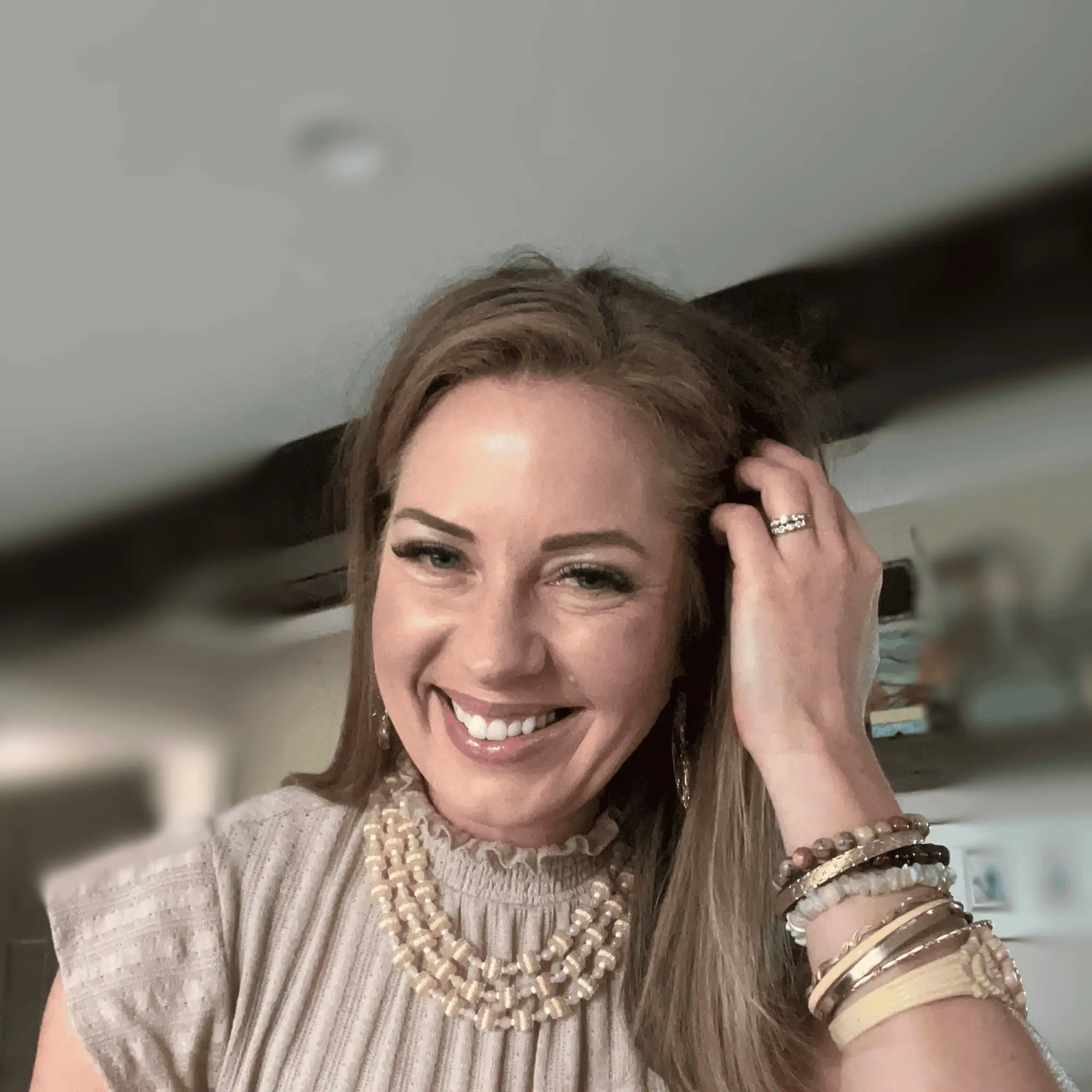 Young smiling female in brown sweater with multiple bracelets.