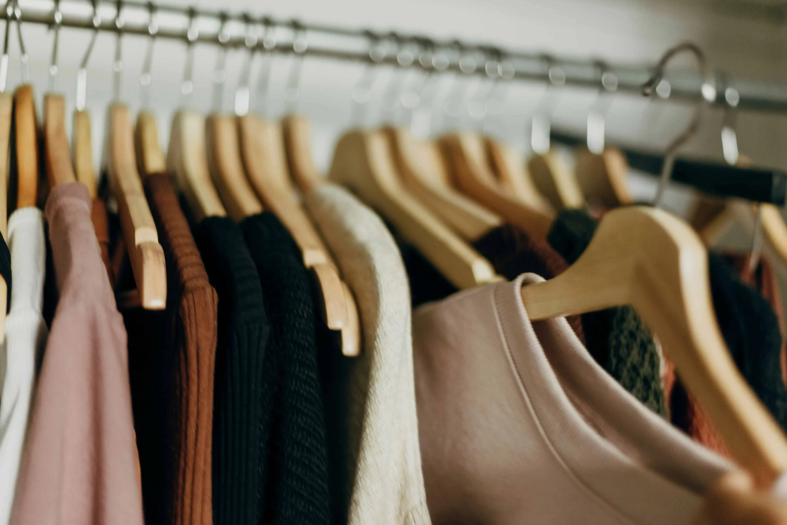 A close-up photo of a row of neutral clothes on hangers. Blending in doesn't have to be your default style.
